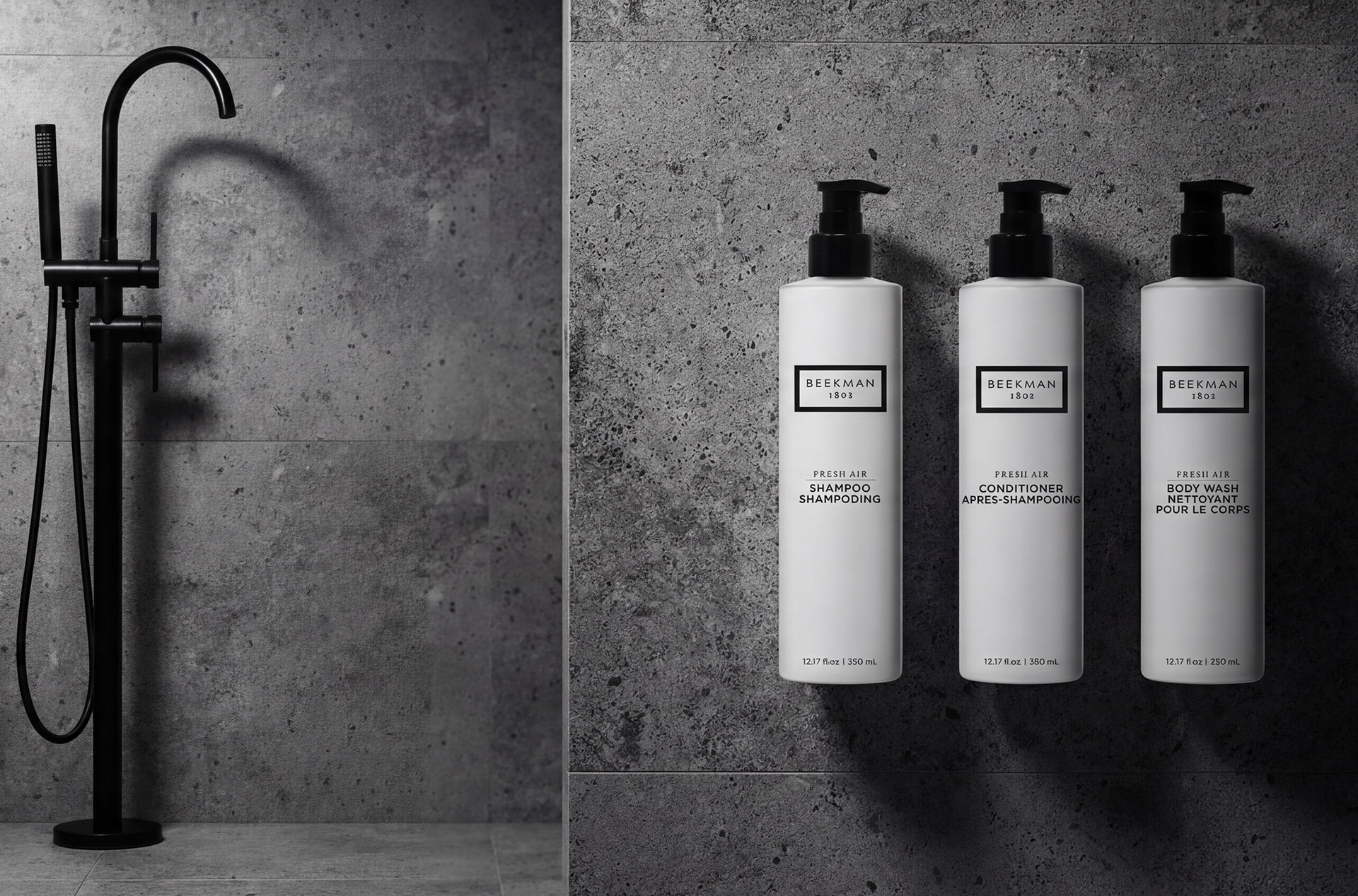 Beekman 1802 Fresh Air shampoo, conditioner, and body wash pump bottles in a hotel shower