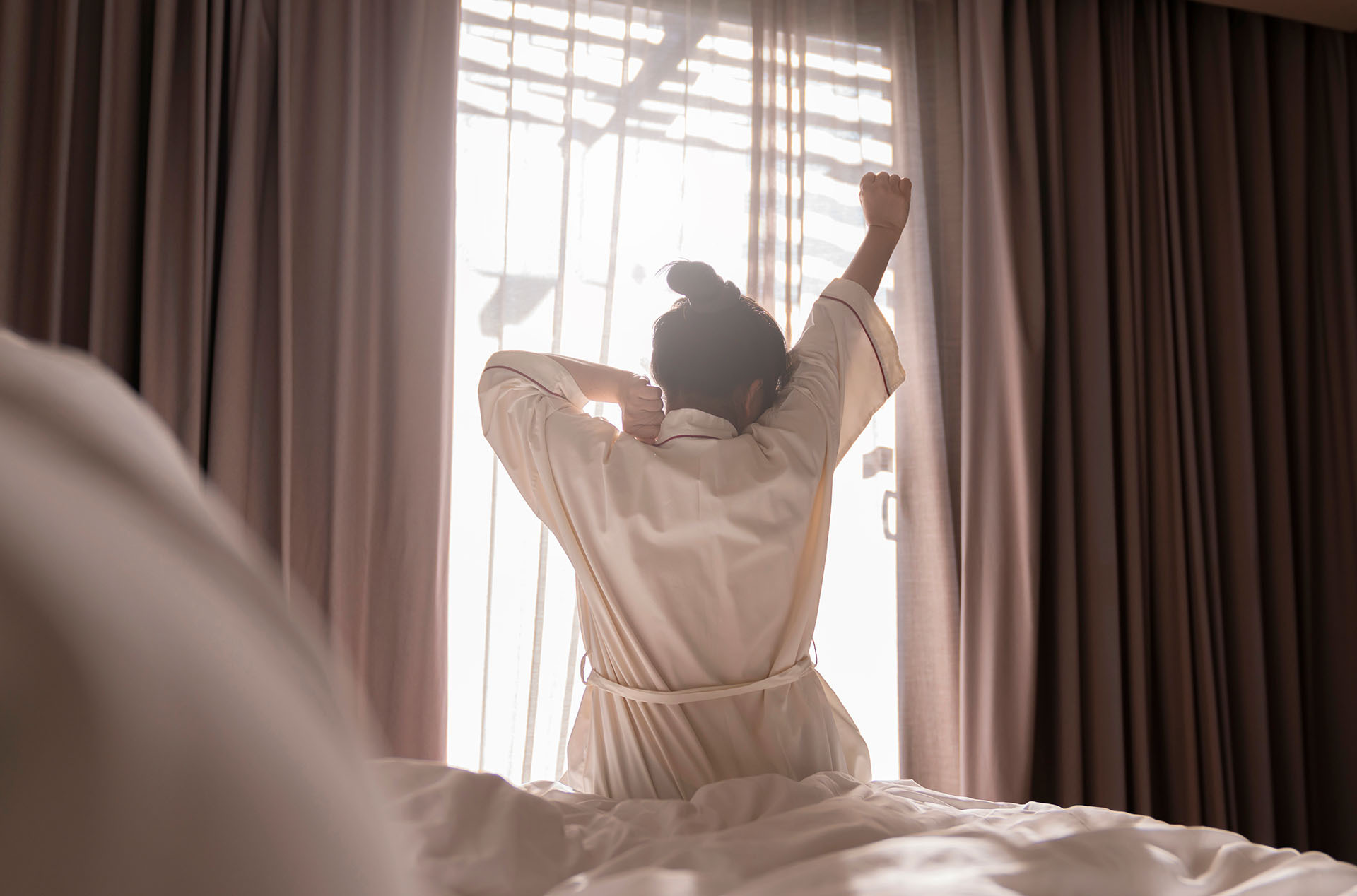 Guest waking up well-rested in a sleep-friendly hotel room designed to support guest sleep quality and reduce hotel noise complaints