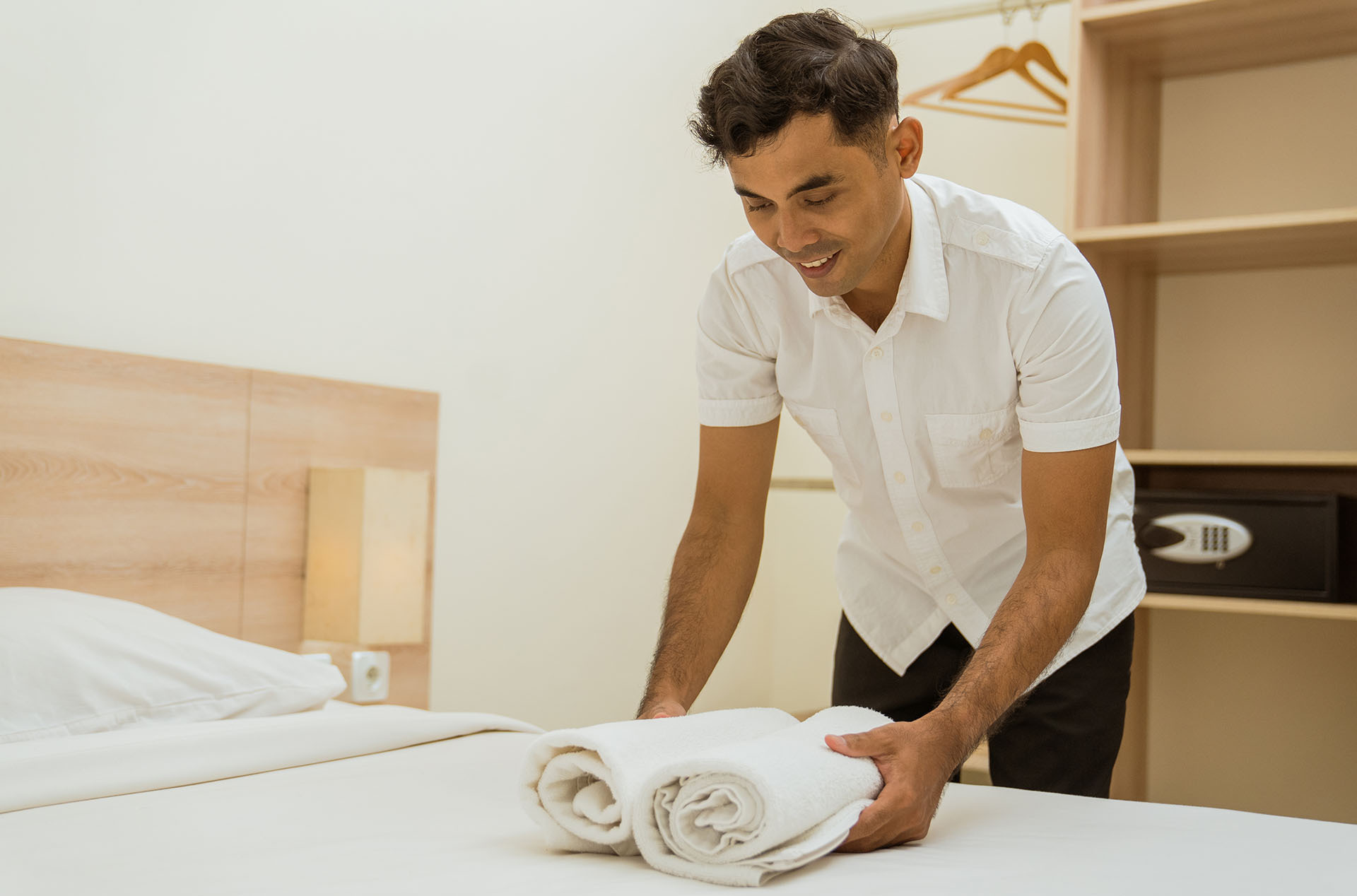 Housekeeper placing clean towels on a guest bed during hotel housekeeping training on linen standards