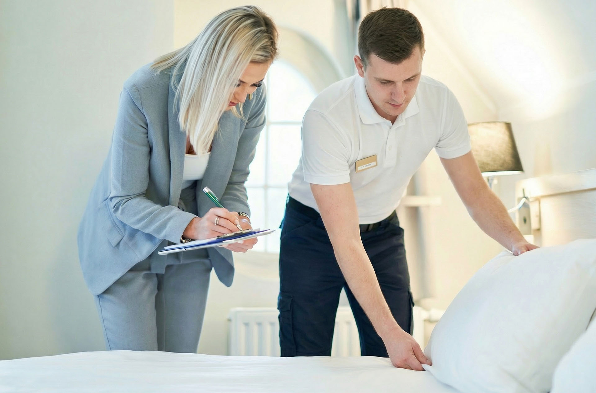 Hotel housekeeping inspection in progress as a supervisor reviews bed-making during a housekeeping staff training program
