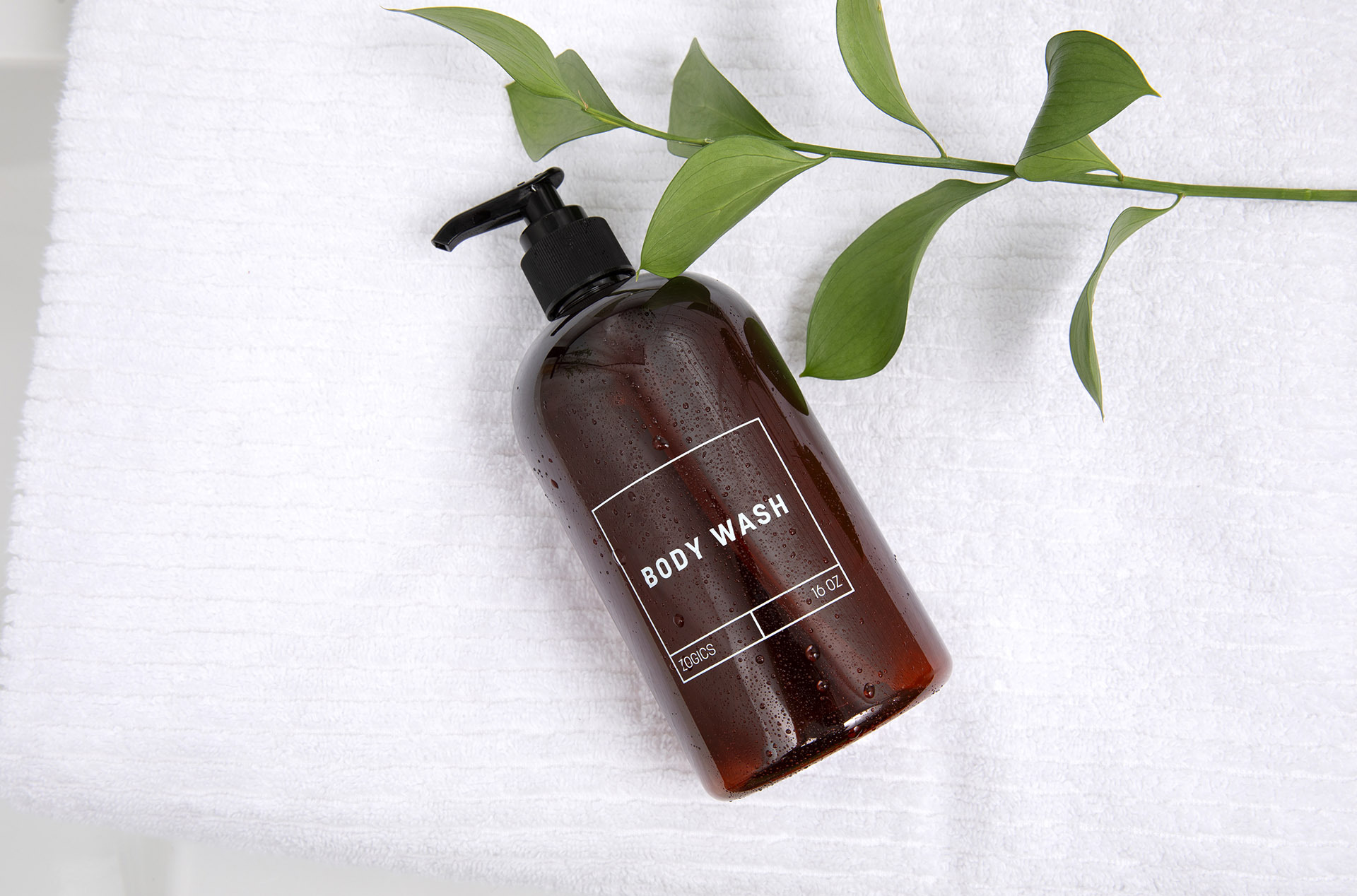 Amber refillable body wash pump bottle on a towel for Airbnb bathroom setup